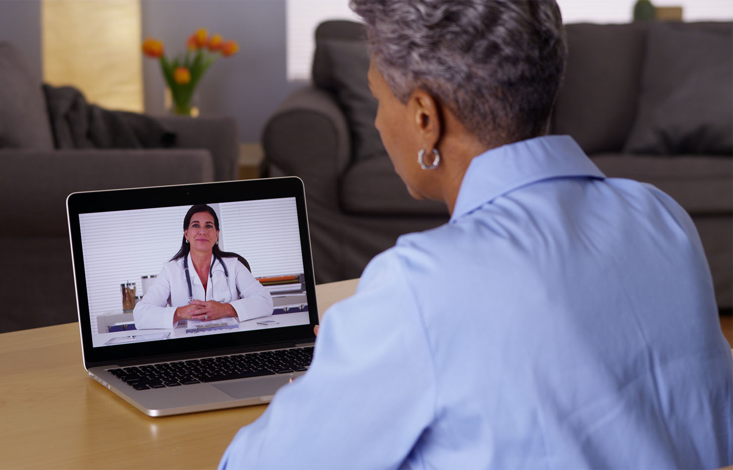 Woman talking to her GP via telehealth using her laptop.