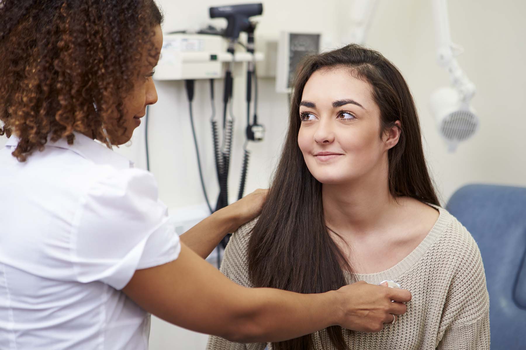 A woman smiling as her GP checks her health.