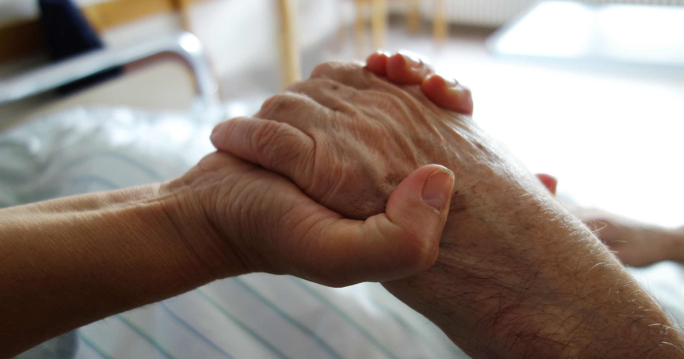 Image of patient at end of life, advance care planning, holding hands.