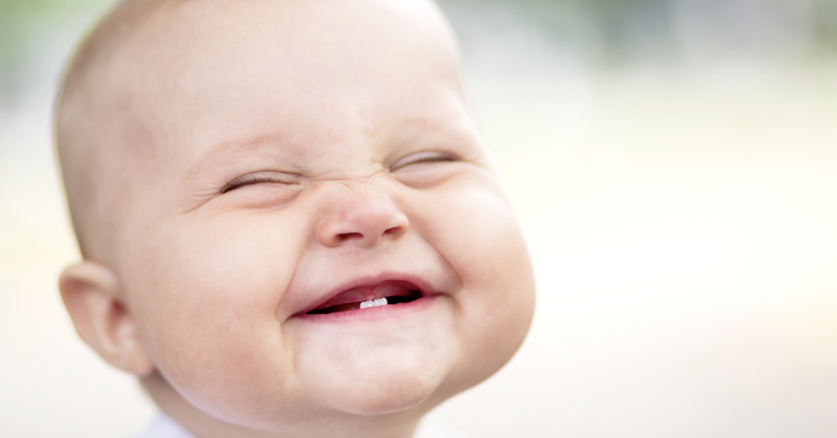 Portrait photograph of a smiling infant.