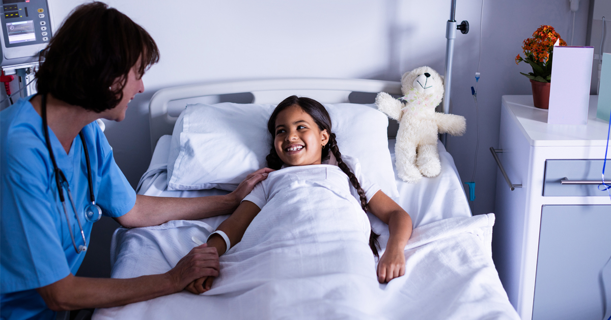 A child in a hospital bed talking with a doctor.