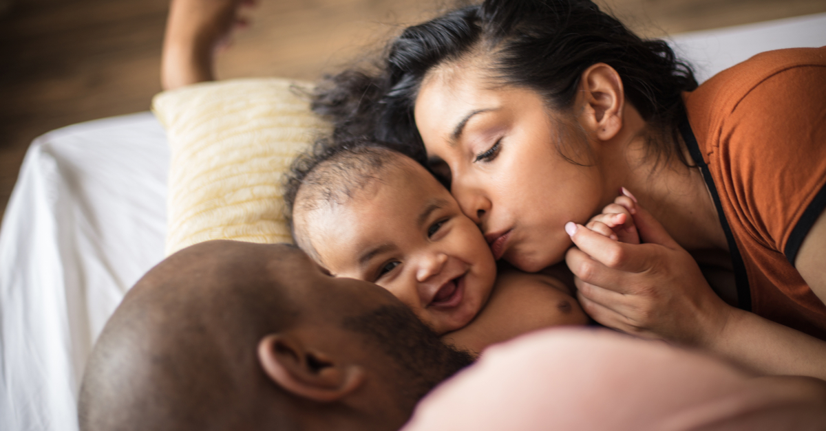 A loving couple hugging their new baby.