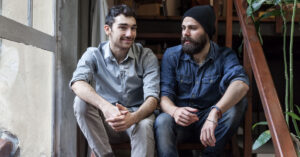 2 men sitting on a set of stairs in conversation.