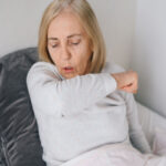 A woman in bed experiencing long COVID symptoms.