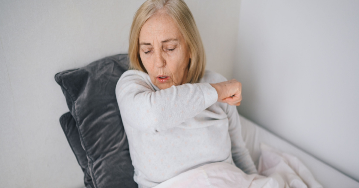 A woman in bed experiencing long COVID symptoms.