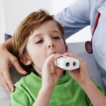 A young child using an asthma inhaler under supervision from a practice nurse.