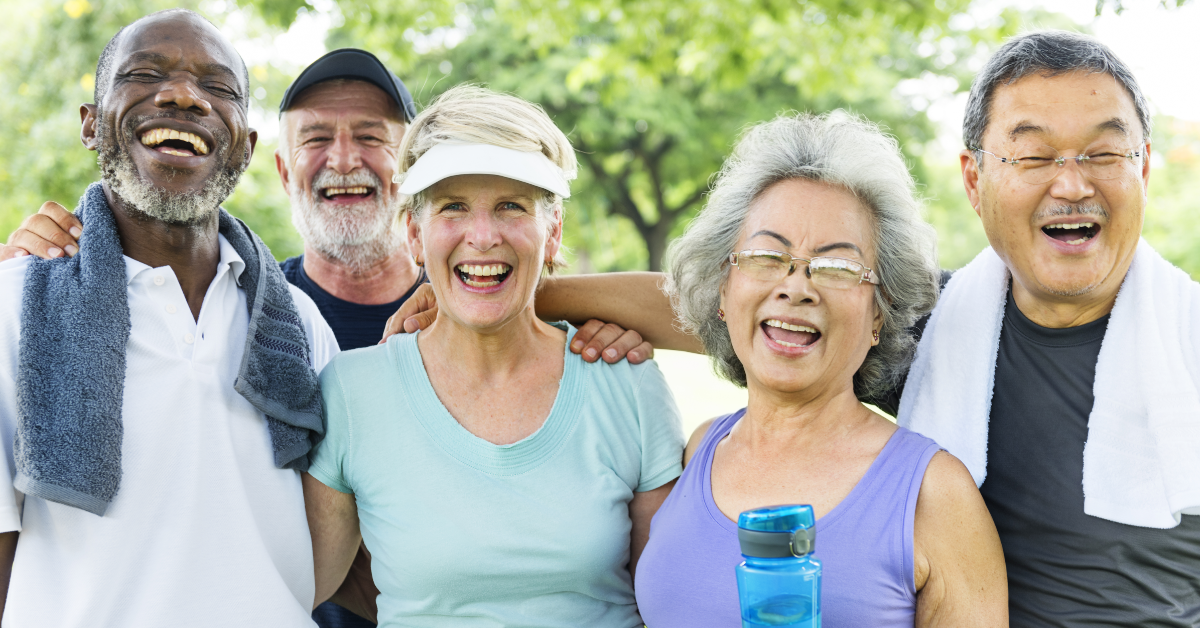 A group of older people smiling as they exercise outdoors.