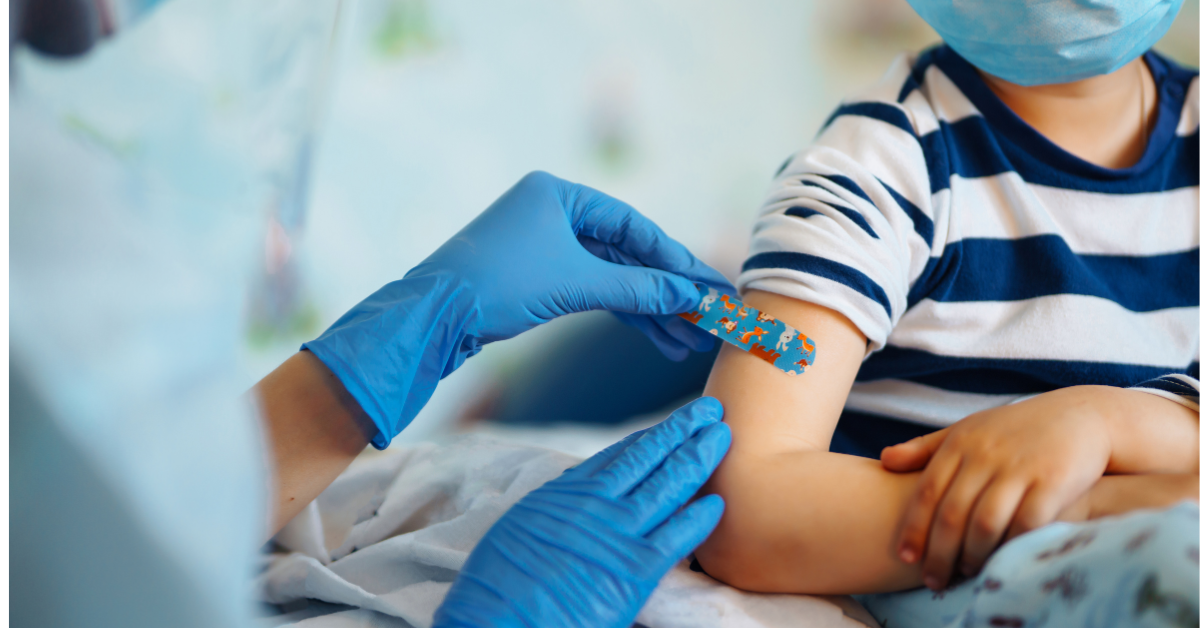 Doctor putting band aid on child after immunisation