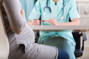 Pregnant women pictured sitting, talking to nurse.