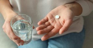 Woman holding a glass of water with pill