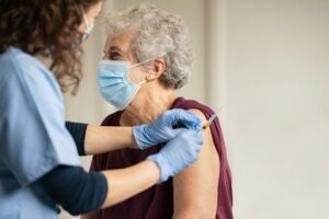 nurse with older female patient, getting a COVID-19 booster