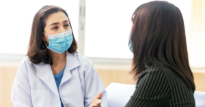 Doctor with face mask talking to patient