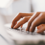 An unidentified general practitioner types at their laptop