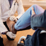 Senior man in wheelchair getting his leg examined by a doctor