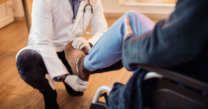 Senior man in wheelchair getting his leg examined by a doctor