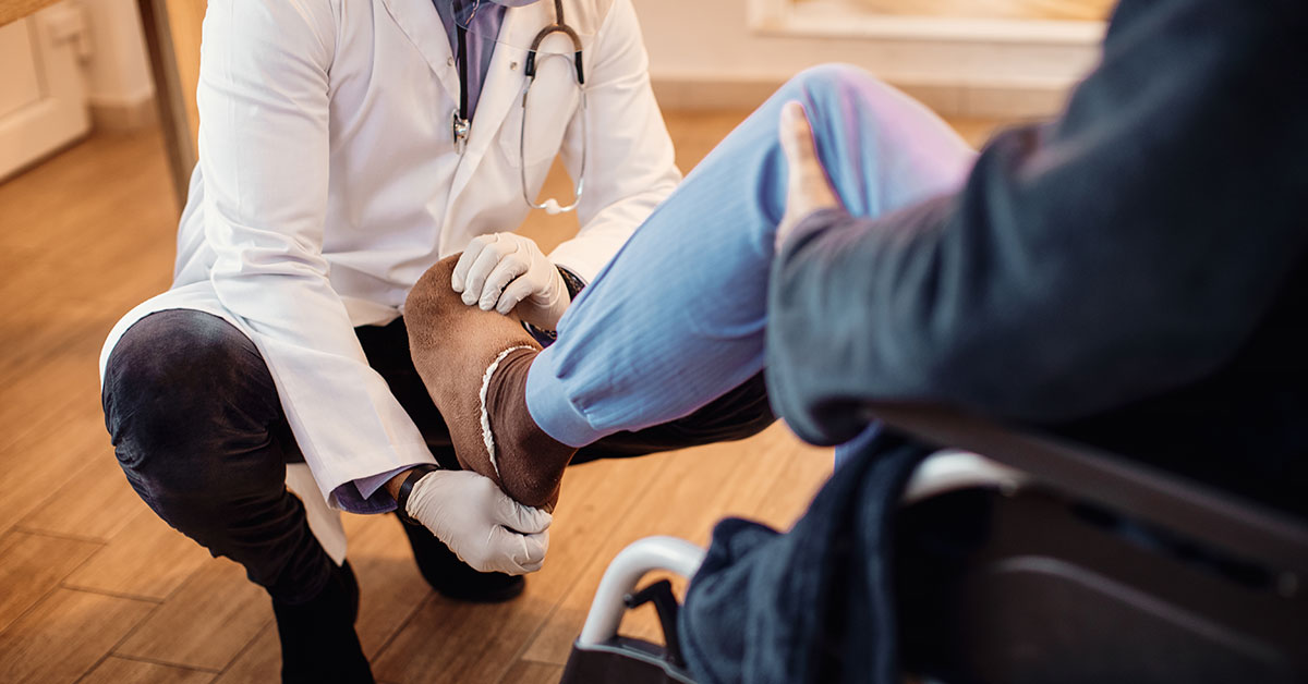 Senior man in wheelchair getting his leg examined by a doctor