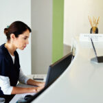 A female health professional works on a computer at a clinic