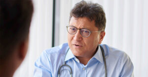 A male general practitioner speaks with a patient about lung cancer screen