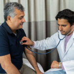 A doctor checks the heart-rate of his patient, a middle-aged man