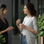 Two young women, health professionals, have a discussion while consuming a coffee