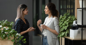 Two young women, health professionals, have a discussion while consuming a coffee