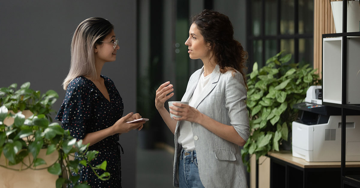 Two young women, health professionals, have a discussion while consuming a coffee