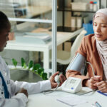A female general practitioner conducts a blood test with a muslim female patient