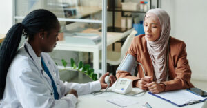 A female general practitioner conducts a blood test with a muslim female patient