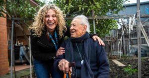 94-year-old Italo poses for a photo with carer Penny at his Thornbury home