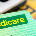 A Medicare card sits in front of a calculator and Australian currency