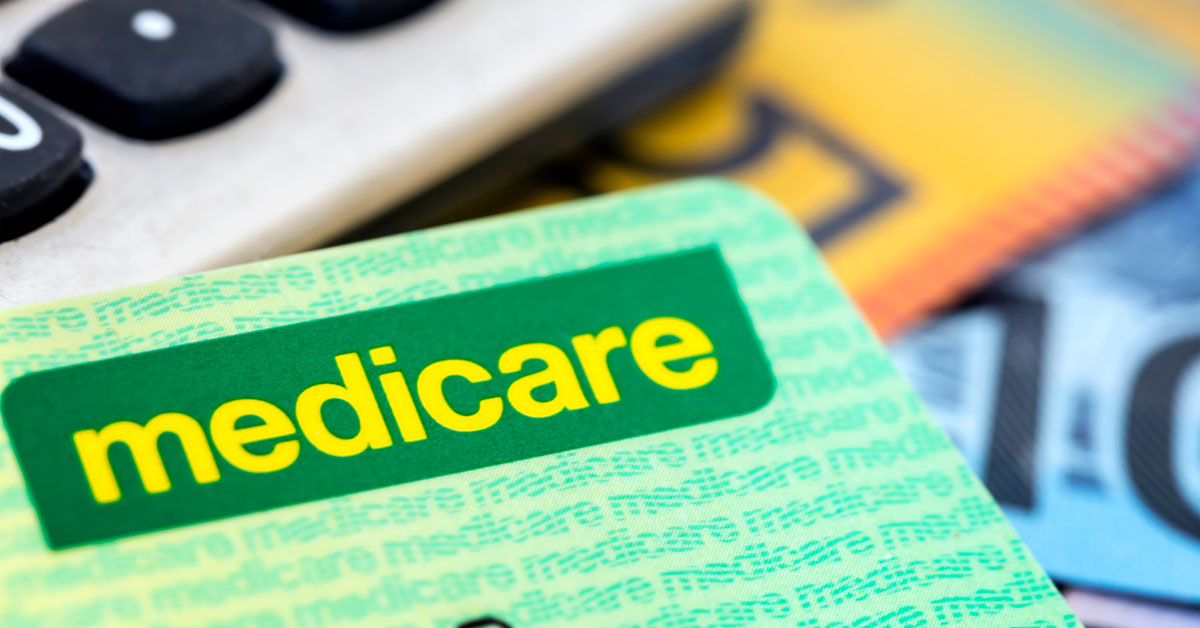 A Medicare card sits in front of a calculator and Australian currency