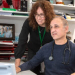 Dr Sam Zagarella, practice co-owner of Niddrie Medical, sits at a desk and looks at the computer alongside practice manager Megan Lay