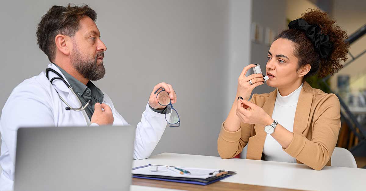 A male general practitioner speaks with a female patient about a new asthma inhaler