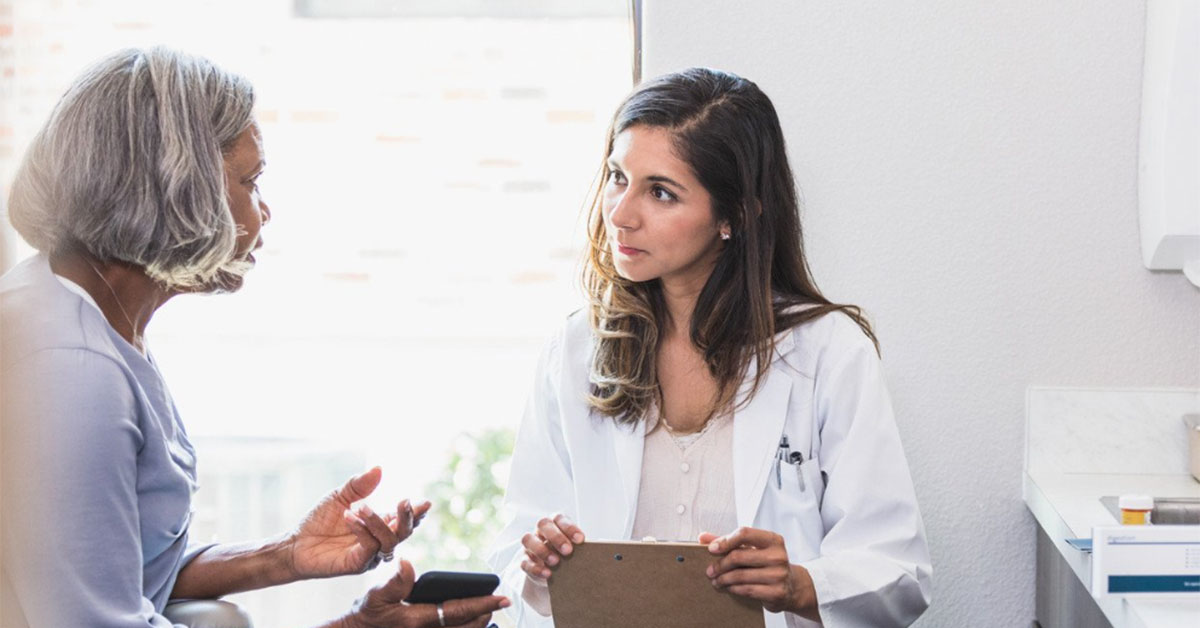 A female GP speaks with a middle-aged female patient