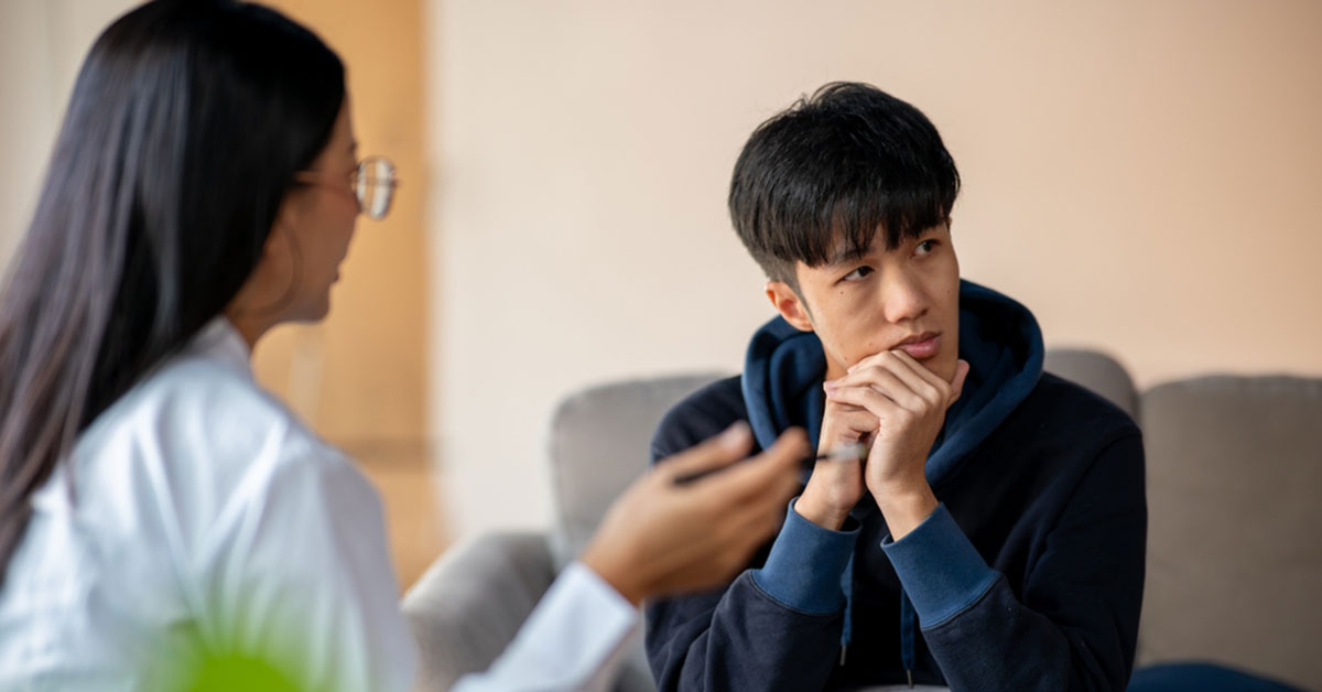 A young man speaks with a mental health professional
