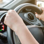 An unidentified person with both hands on the steering wheel