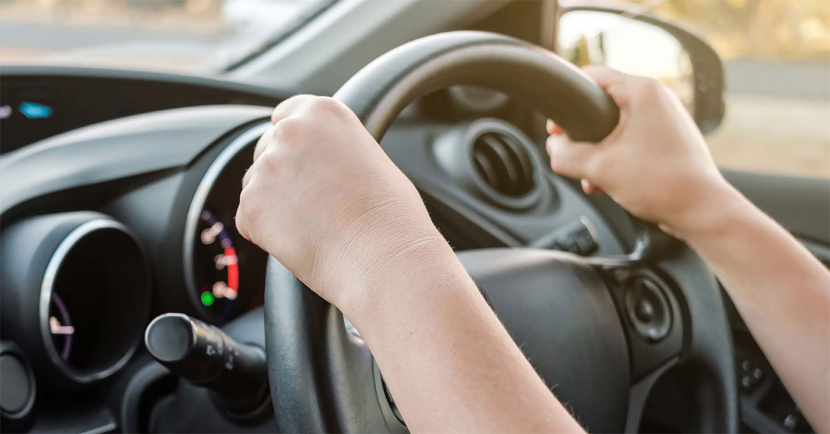 An unidentified person with both hands on the steering wheel