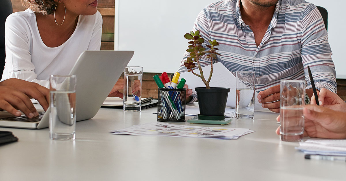 Health care professionals sit at a meeting table to discuss how to improve health care outcomes