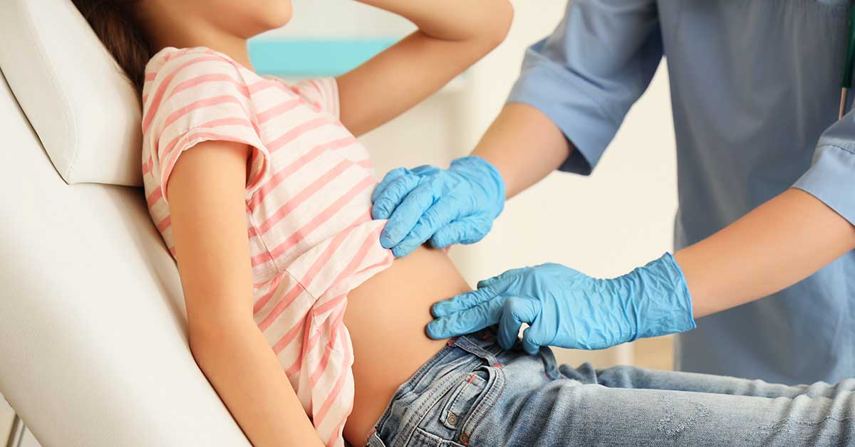 Female doctor examining teenage girl with appendicitis in clinic, closeup