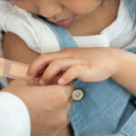 A doctor places a band aid over the upper arm of a young girl who had just received her flu vaccination