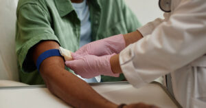 Close up image of nurse preparing patient for blood test and putting tourniquet on arm in procedure room at clinic.