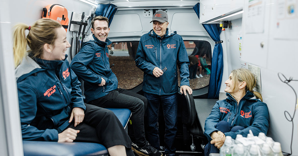 Volunteers for Street Side Medics - a free mobile medical service to people experiencing homelessness - share a joke together