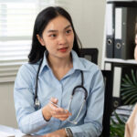 A female general practitioner speaks with a middle aged woman about menopause symptoms