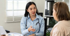 A female general practitioner speaks with a middle aged woman about menopause symptoms