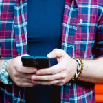 Unidentified man wearing flannel shirt uses his mobile phone