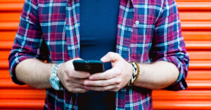 Unidentified man wearing flannel shirt uses his mobile phone
