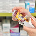 A clinician takes a blister pack of tablets out of a box.
