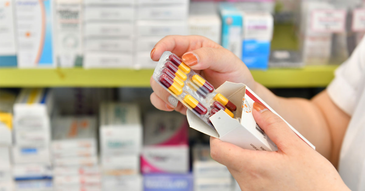A clinician takes a blister pack of tablets out of a box.