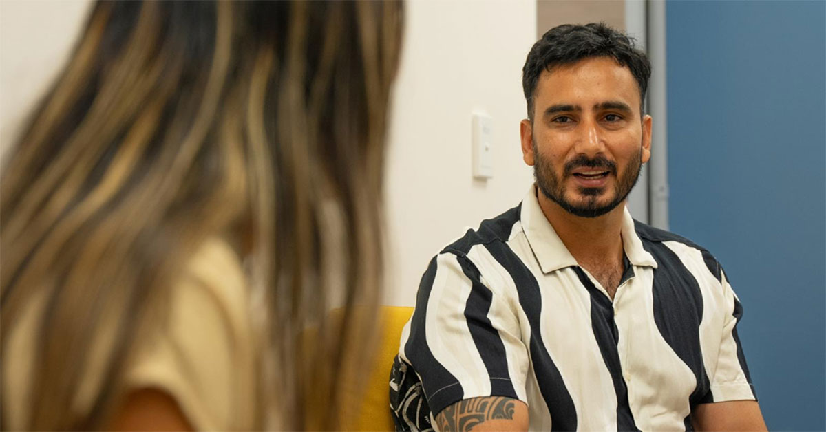 A man in his 30s speaks with a health professional about his mental health