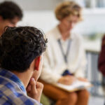 School students sit in a circle listening to a presenter.